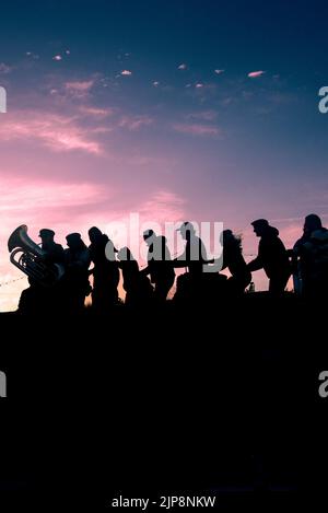 La silhouette des gens formant une ligne de conga avec des musiciens de iThe Old Time marins qui se produisent à l'amphithéâtre Newquay Orchard de Cornwall. Banque D'Images