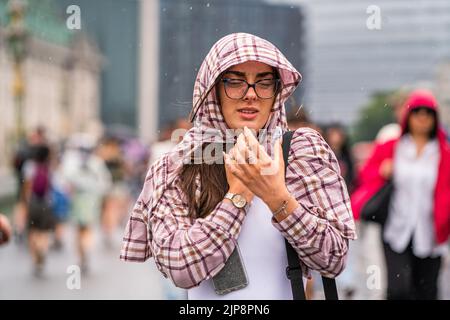 Westminster Londres, Royaume-Uni. 16 août 2022 . Un piéton sur le pont de Westminster couvre sa tête pendant les averses de pluie pendant que la sécheresse se termine après le temps sec prolongé et l'été le plus sec en 46 ans, alors que le bureau met émet un avertissement jaune pour les orages et les inondations éclair . Credit. amer ghazzal/Alamy Live News Banque D'Images