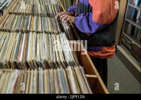 Femme à la recherche de musique dans un magasin local Banque D'Images