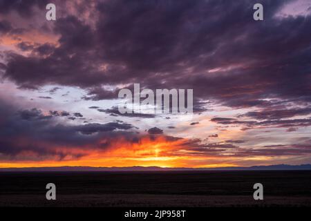 Les nuages orange et violet surplombent les plaines du Colorado avec des montagnes au loin Banque D'Images