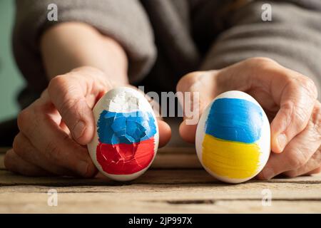 Deux oeufs de poulet, l'un avec le drapeau de la Russie est cassé, et le second avec le drapeau de l'Ukraine est entier entre les mains d'une femme, la Russie a perdu la guerre Banque D'Images