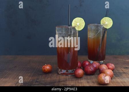 Cocktails en prune avec pruneaux sur table en bois et fond noir Banque D'Images