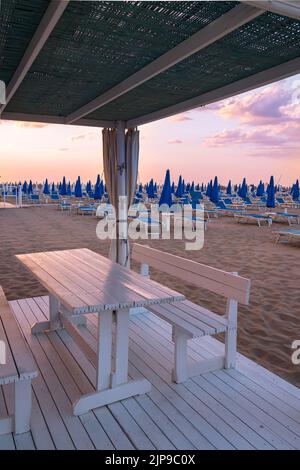 Vue sur les chaises longues vides à la plage de sable de Rivazzurra, Rimini, Italie au coucher du soleil Banque D'Images