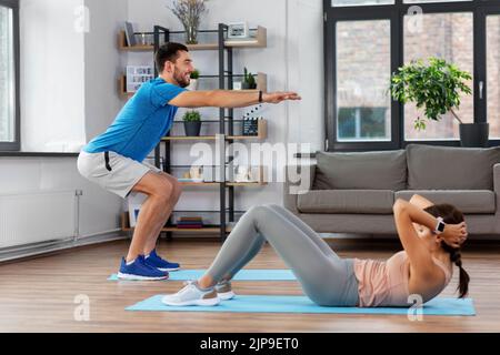 joyeux jeune homme et femme s'exerçant à la maison Banque D'Images