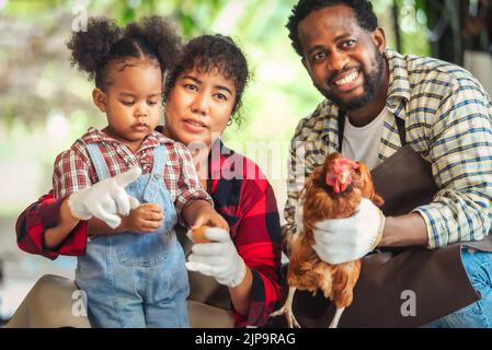 Portrait de l'homme et de la femme africains enseignant aux enfants d'élever des poulets à la ferme Banque D'Images