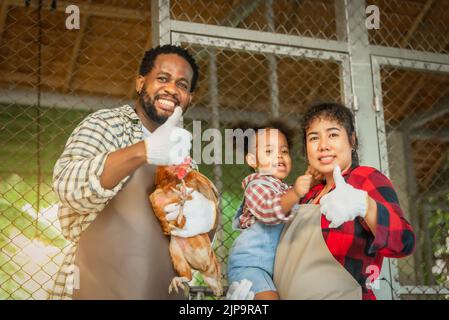 Portrait de l'homme et de la femme africains enseignant aux enfants d'élever des poulets à la ferme Banque D'Images