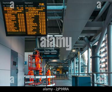 Entretien des panneaux d'information pour les départs à la gare de Leeds par le personnel de Network Rail, West Yorkshire, Angleterre, Royaume-Uni Banque D'Images