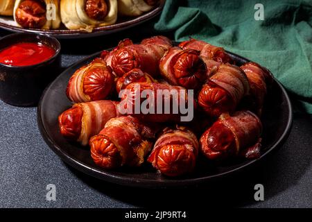 Recette traditionnelle de plat de Noël Pigs en couvertures, saucisses enveloppées dans le bacon, pâtisserie feuilletée au four hot dogs rouleaux avec des branches d'arbre de Noël, décorati Banque D'Images