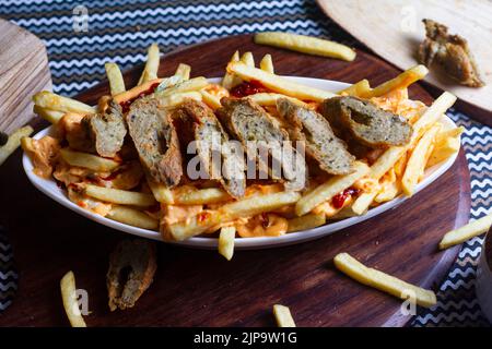 Plat de FRITES CHEESY SEEKH au café restaurant. Plat de restauration rapide américain, composé de frites recouvertes de fromage. Banque D'Images