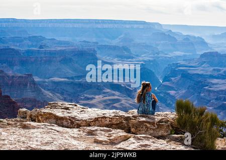 Le coucher du soleil approche du plateau sud, parc national du Grand Canyon, Arizona. Femme assise au bord du canyon surplombant le canyon. Fleuve Colorado. Banque D'Images