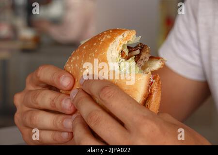 Gros plan de la main tenant un hamburger partiellement mangé Banque D'Images