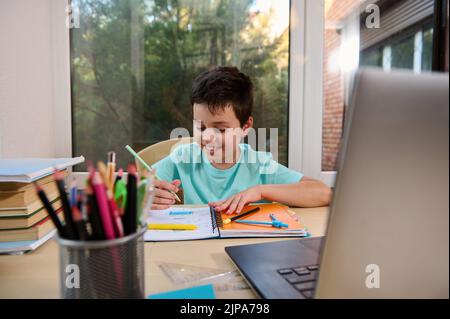 Bon élève qui fait ses devoirs, apprend la géométrie assis sur un ordinateur portable pendant la leçon en ligne. Éducation en ligne homeschooling Banque D'Images