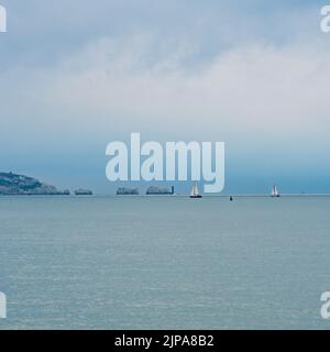 Milford-on-Sea, Hampshire, Royaume-Uni, 16th août 2022, Météo. Des averses lourdes accompagnent les nuages sombres comme la pluie nécessaire tombe sur sec, parché sud de l'Angleterre. Des voiliers blancs passent devant le phare de Needles sur l'île de Wight. Crédit : Paul Biggins/Alamy Live News Banque D'Images