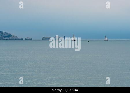 Milford-on-Sea, Hampshire, Royaume-Uni, 16th août 2022, Météo. Des averses lourdes accompagnent les nuages sombres comme la pluie nécessaire tombe sur sec, parché sud de l'Angleterre. Des voiliers blancs passent devant le phare de Needles sur l'île de Wight. Crédit : Paul Biggins/Alamy Live News Banque D'Images