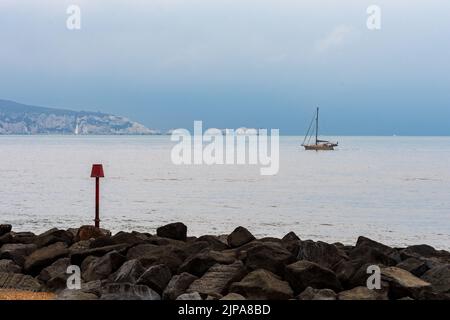 Milford-on-Sea, Hampshire, Royaume-Uni, 16th août 2022, Météo. Des averses lourdes accompagnent les nuages sombres comme la pluie nécessaire tombe sur sec, parché sud de l'Angleterre. Un bateau passe devant le phare de Needles sur l'île de Wight. Crédit : Paul Biggins/Alamy Live News Banque D'Images