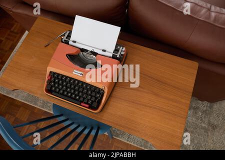 Photographie du dessus d'une machine à écrire Underwood 20 des années 1970 sur un bureau en teck, avec une feuille de papier dans la machine à écrire. Banque D'Images