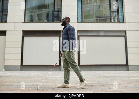 Portrait complet d'un homme aveugle souriant marchant dans la ville et utilisant la canne, espace de copie Banque D'Images