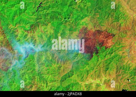 McKinney, Californie, États-Unis. 6th août 2022. Plus d'une semaine après son allumage, le feu McKinney a continué à brûler à travers la forêt nationale de Klamath, dans le nord de la Californie. C'était le plus grand et le plus meurtrier feu de forêt de l'État jusqu'à présent en 2022. Le paysage marqué et la fumée des feux qui brûlent activement sont visibles dans les images ci-dessus. Les images ont été acquises sur 6 août 2022, par l'imageur de sol opérationnel (OLI) sur Landsat 8. L'image fausse couleur (à droite) était composée de lumière infrarouge à ondes courtes, proche infrarouge et verte. Cette combinaison de bandes (6-5-3) coupe la fumée pour révéler le bu Banque D'Images