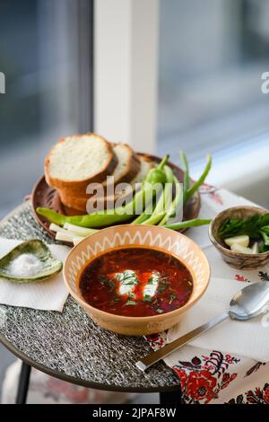Borscht ukrainien traditionnel. Bol en argile de soupe de racine de betterave rouge borsch à la crème blanche. Banque D'Images