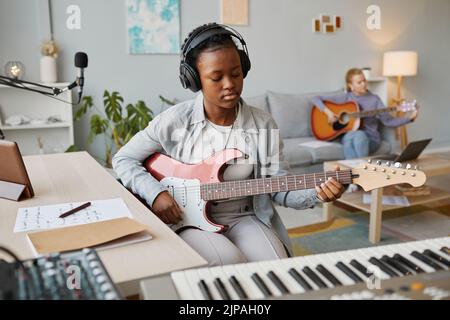 Portrait d'une jeune femme noire jouant de la guitare électrique en studio et composant de la musique, espace de copie Banque D'Images