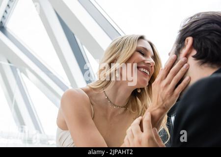 Vue à angle bas de la femme souriante touchant le petit ami brunette dans le restaurant Banque D'Images