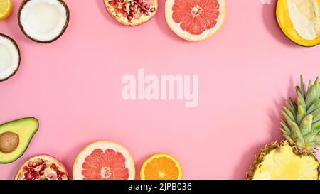 Cadre tropical d'été fait avec des fruits exotiques sur fond rose pastel. Pose à plat. Banque D'Images