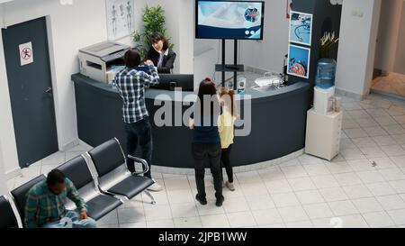 Réception et salle d'attente très fréquentées avec divers patients, rendez-vous médical pour une visite de contrôle. Attente dans le hall de la clinique pour assister à la consultation de soins de santé, le soutien médical. Banque D'Images