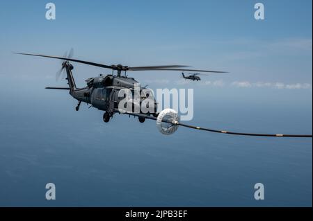 Un hélicoptère HH-60G Pave Hawk est ravitaillé par un escadron de sauvetage HC-130J combat King II du 39th e Escadron lors d'une compétition de tir de dinde au large de la Floride sur 16 juin 2022. Au cours de la compétition, les membres de l'équipage ont concouru sur des compétences telles que l'emploi d'armes d'avion, le ravitaillement en vol d'hélicoptère, la navigation dégradée, la recherche dégradée et le hissage confiné. (É.-U. Photo de la Force spatiale par le premier Airman Thomas Sjoberg) Banque D'Images