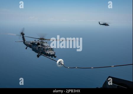 Un hélicoptère HH-60G Pave Hawk est ravitaillé par un escadron de sauvetage HC-130J combat King II du 39th e Escadron lors d'une compétition de tir de dinde au large de la Floride sur 16 juin 2022. Au cours de la compétition, les membres de l'équipage ont concouru sur des compétences telles que l'emploi d'armes d'avion, le ravitaillement en vol d'hélicoptère, la navigation dégradée, la recherche dégradée et le hissage confiné. (É.-U. Photo de la Force spatiale par le premier Airman Thomas Sjoberg) Banque D'Images