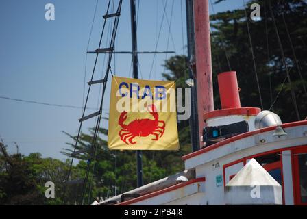 Un drapeau de capture de crabe volant de la gréement sur un bateau de pêche amarré le long de la côte centrale de Californie, un jour d'été contre un ciel bleu. Banque D'Images