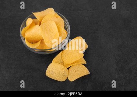 Chips de pomme de terre sur une surface noire en pierre dans une soucoupe Banque D'Images