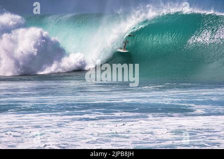 Surfeur caché dans le tube d'une vague de rupture sur Maui. Banque D'Images