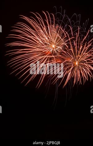 Feux d'artifice rouges, orange et violets dans le ciel nocturne. Banque D'Images