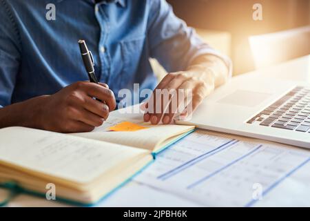Il met ses idées sur papier. Un designer masculin méconnaissable prend des notes lorsqu'il travaille dans son bureau. Banque D'Images
