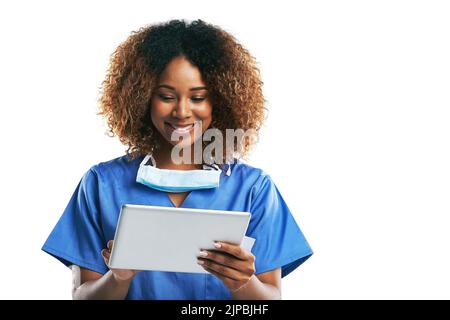 Internet fournit toutes les dernières informations dont elle a besoin. Photo en studio d'une jeune infirmière attrayante à l'aide d'une tablette numérique sur fond blanc. Banque D'Images