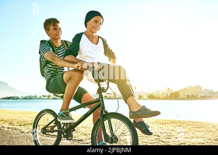 Votre frère est votre premier ami. Un jeune garçon donnant à son frère cadet un ascenseur sur un vélo à l'extérieur. Banque D'Images