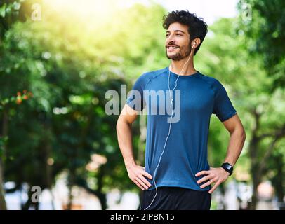 Un jeune homme sportif qui écoute de la musique tout en faisant de l'exercice à l'extérieur. Banque D'Images