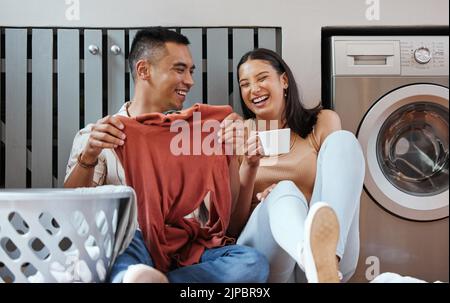 Couple insouciant et drôle faisant la lessive et se détendre ensemble à la maison le matin. Les amateurs de rire, de glouffe et de jeu en riant et en riant Banque D'Images