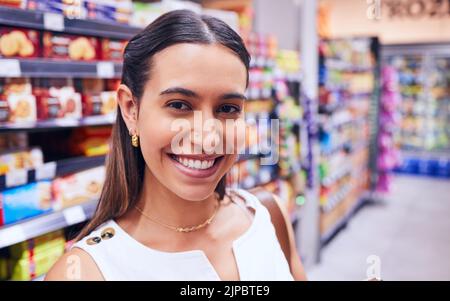 Shopping, épicerie et consumérisme avec une jeune femme dans une épicerie, un magasin de détail ou une allée de supermarché. Portrait d'une femme debout en gros plan Banque D'Images