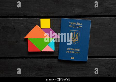 Une maison en bois en cubes se trouve à côté d'un passeport étranger biométrique ukrainien sur la table, Native Home Ukraine Banque D'Images