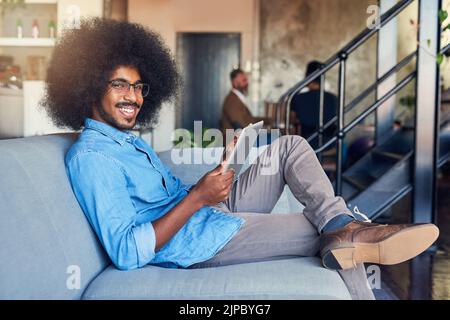 La meilleure façon de faire preuve de créativité, c'est le confort. Portrait rogné d'un jeune homme beau designer travaillant sur une tablette au bureau. Banque D'Images