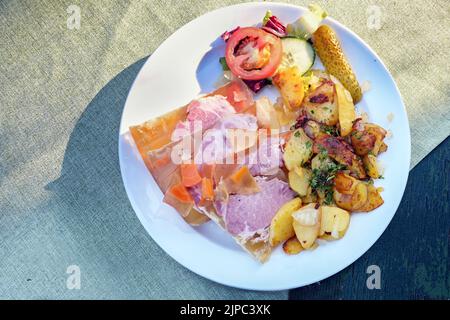 Sauerfleisch mit Bratkartoffeln ou viande aigre marinée à l'aspique avec des pommes de terre frites, plat traditionnel allemand et autrichien sur une plaque blanche et un rustique Banque D'Images