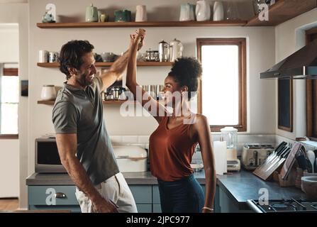 Heureux, dans l'amour et la danse tandis qu'un couple interracial ont le plaisir et de profiter du temps ensemble dans la cuisine maison. Mari et femme partageant une danse pendant Banque D'Images