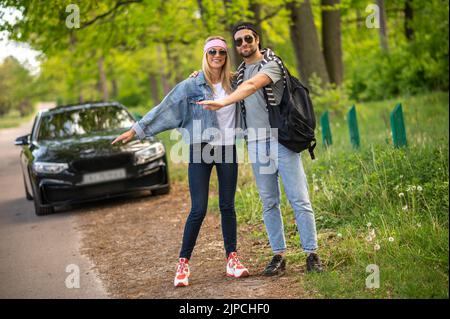 Les jeunes dans la forêt arrêtent la voiture et ont l'air joyeux Banque D'Images