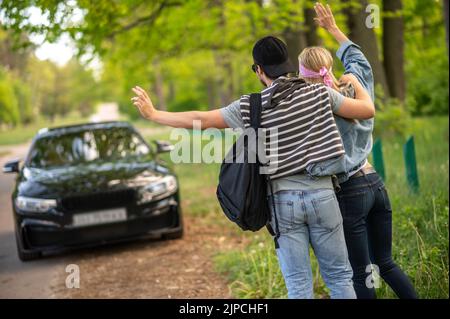 Les jeunes dans la forêt arrêtent la voiture et ont l'air joyeux Banque D'Images