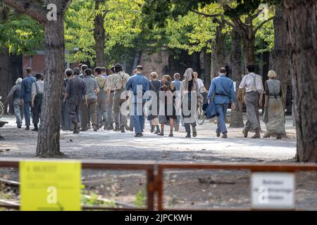 Emmerich, Allemagne. 16th août 2022. Les extras marchent dans la partie publique du Landschaftspark dans le cadre du tournage du nouveau film "les Hommages de Panem: Chanson de l'oiseau et du serpent". Le tournage du préquel de la série de films 'les Hommages de Panem' a commencé cette semaine dans le Landschaftspark Duisburg. Pour le film, environ 3000 extras avaient été recherchés pour participer à l'un des huit jours de tournage devant l'appareil photo dans la région de Duisburg. Credit: Christoph Reichwein/dpa/Alay Live News Banque D'Images