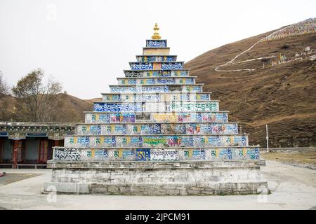Stupa Tibétain en forme de pyramide faite de dalles de pierre colorées, imprimé avec écriture bouddhiste en langue tibétaine standard, monastère de Tagong. Banque D'Images