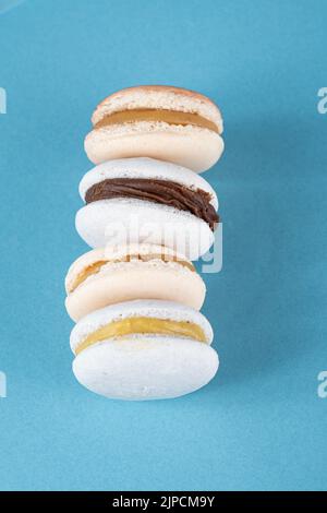 Gros plan de macarons avec garniture de ganache au chocolat et dulce de leche empilée sur une assiette bleue vue de dessus. Banque D'Images