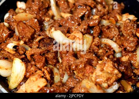 Mise au point sélective de morceaux et cubes de viande rouge de bœuf grillée à l'huile, morceaux d'oignon, ail, épices, champignons, Sauce soja et farine de maïs, cuisine chinoise Banque D'Images