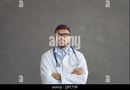 Portrait d'un jeune médecin sérieux dans un manteau de laboratoire regardant vers le haut et pensant au travail Banque D'Images